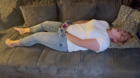 Blondes Babe in engen Jeans genießt multiple Orgasmen auf der Couch, während sie einen Satisfyer benutzt