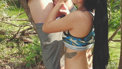 Bella bruna in bikini con lunghi capelli fa un pompino all'aperto